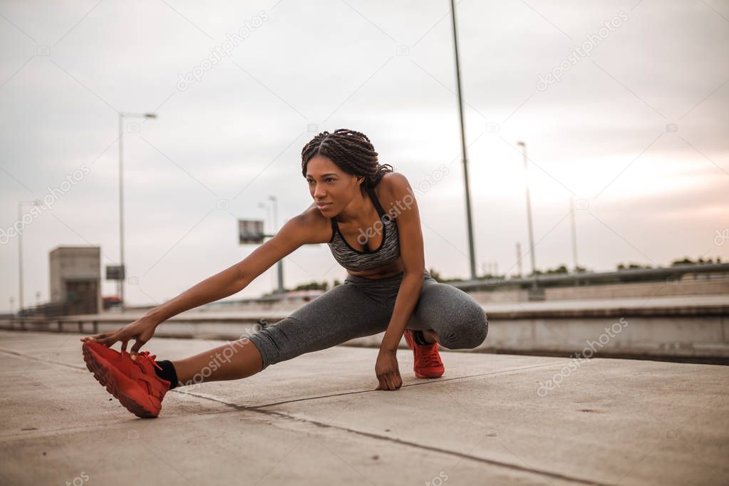 African american woman is stretching before jogging