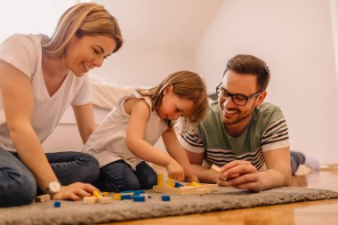 Katında oturan ve oyuncakları ile oynarken mutlu genç aile portresi