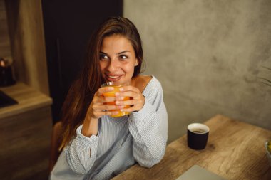 Pijama giymiş ve sabah portakal suyu içme güzel genç esmer portresi