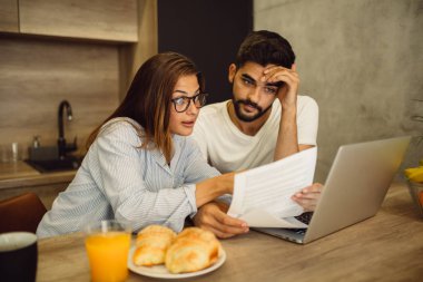 Genç çift ev mutfak evde kahvaltı yaparken bütçeleme için belgelerine yapıyor