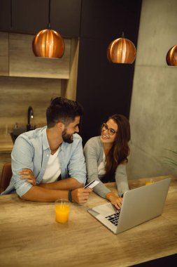 Genç çift kredi kartı ve evde laptop ile online alışveriş.