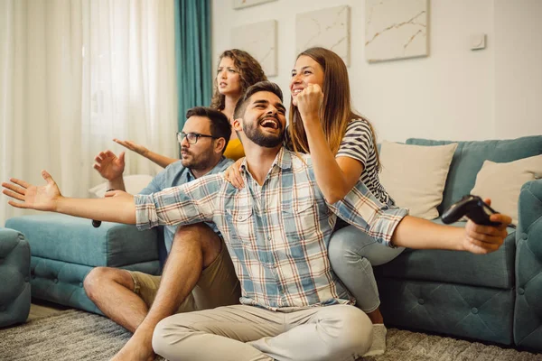 Evde video oyunu oynayan heyecanlı arkadaşlar.