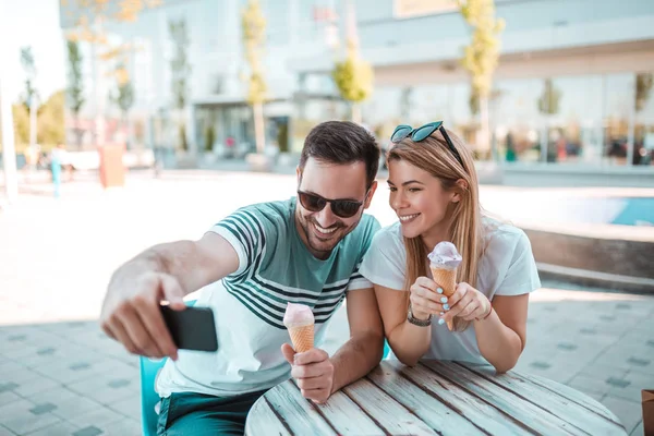 若者の肖像画カップル屋外に座っているコーンのアイスクリームを食べながら Selfie を取って — ストック写真