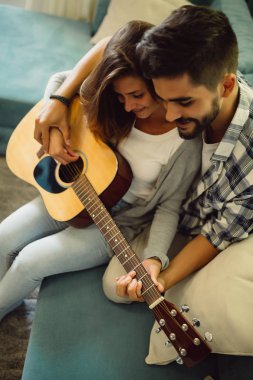 Onu gitar çalmayı öğretiyor. Yakışıklı genç sakallı adam gitar çalmayı kız arkadaşı öğretim.