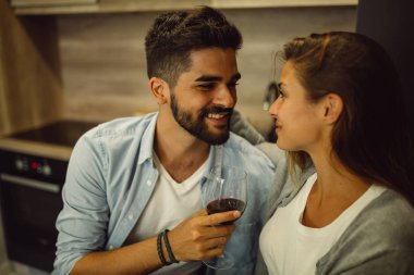 Genç çift evde mutfakta bir bardak şarap tutarken sarılma