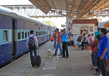 Margao, Goa, Hindistan: Ocak 20, 2011: kalabalık tren istasyonu platformu. Girme ve platformun sol tarafta tren hareket birçok yolcular, özellikle Hint etnik köken. Refresment köşk arka planda. Gün vakti.