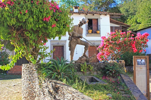 Begonviller ve arka planda eski tarz ev ile madenci heykeli. Tarihi maden kasabası San Sebastian del Oeste, Jalisco eyaleti, Meksika.