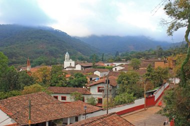Cityscape, San Sebastian del Oeste, Jalisco eyaleti, Meksika. Arka planda ön planda ve sisli Sierra Madre dağlarında tarihi evlerin ve kilise kulesinin kahverengi tuğla çatılar.