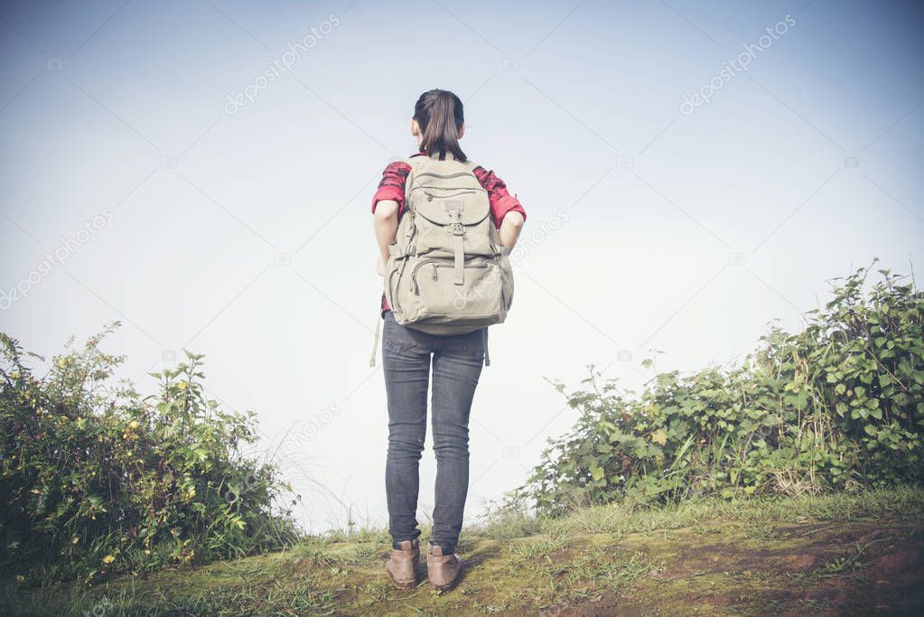 Hipster young girl with backpack enjoying sunset on peak of fogg
