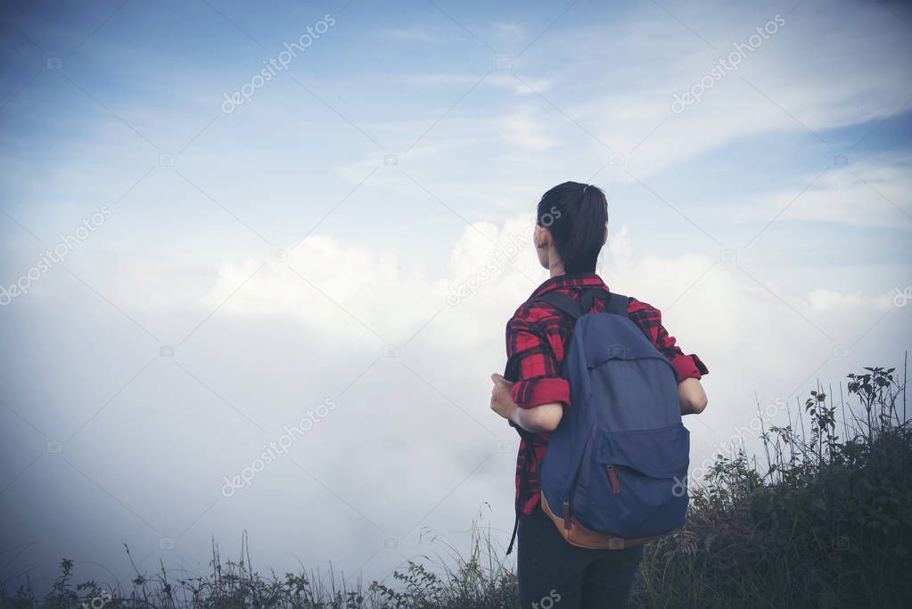 Hipster young girl with backpack enjoying sunset on peak of fogg