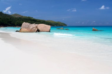 Mavi su ve mavi gökyüzü ve beyaz kum ve kaya ile plaj