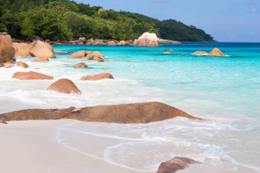 Mavi su ve mavi gökyüzü ve beyaz kum ve kaya ile plaj