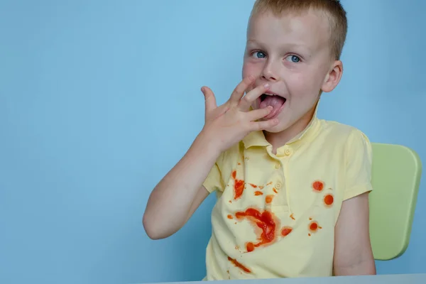 Hladový Chlapec Olizuje Svačinu Prstů Skvrny Žlutém Tričku Izolované Modrém — Stock fotografie