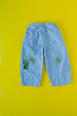 Pantolon üzerindeki çimen lekeleri. Sarı arka planda izole edilmiş.