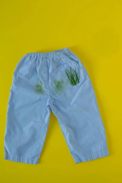 Pantalones de bebé en manchas de hierba. Aislado sobre fondo amarillo — Foto de Stock