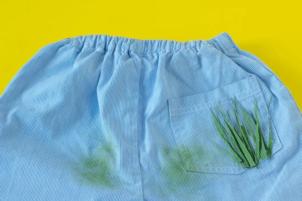 Pantalones de bebé en manchas de hierba. Aislado sobre fondo amarillo — Foto de Stock