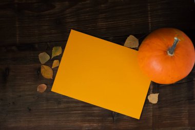 Kahverengi arka planda sarı yaprakların yanında turuncu balkabağı, üst manzara. Mesaj için yer. Cadılar Bayramı geçmişi. Yüksek kalite fotoğraf