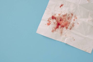 Mavi arka planda izole edilmiş kağıt peçetedeki kan. Yüksek kalite fotoğraf