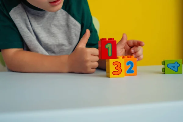 Close up de crianças mãos jogando cubos coloridos com números na mesa — Fotografia de Stock