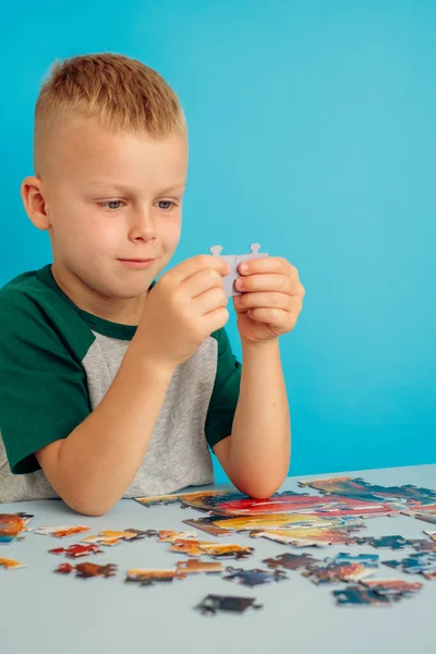 Porträtt av en pojke som håller i pussel och sitter vid bordet — Stockfoto