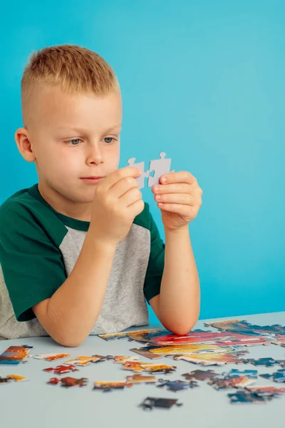 Porträtt av en pojke som förbinder pussel.på en blå bakgrund — Stockfoto