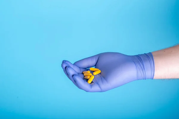 Pastillas Amarillas Mano Del Médico Sobre Fondo Azul Con Copyspace — Foto de Stock
