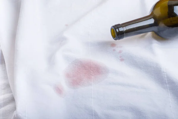 Turned over the bottle and spilled exquisite red wine on a white T-shirt. Place for text — Stock Photo, Image