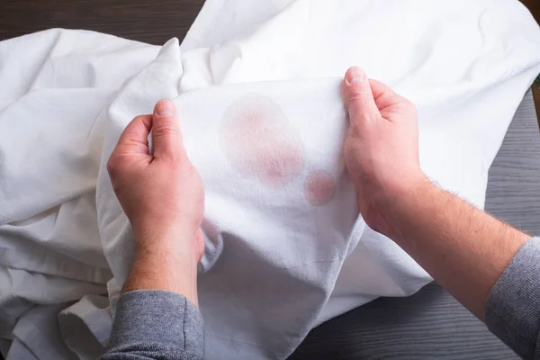 Mans reicht Kleidungsstücke mit einem Fleck vom Wein.Draufsicht — Stockfoto