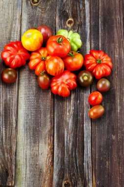 Eski ahşap bir masanın üstünde taze kırmızı domatesler