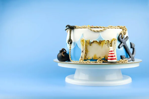 Cake for the child\'s birthday  on a pirate theme, decorated with sea waves  a skull, an anchor, a bomb, a buoy, an old scroll on a blue background. Picture for a menu or a confectionery catalog.