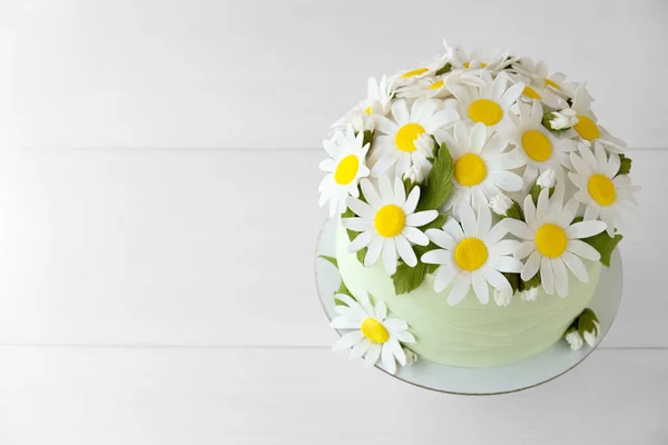 Cake decorated with chamomile flowers from mastic on a white wooden table. Picture for a menu or a confectionery catalog. Top view.