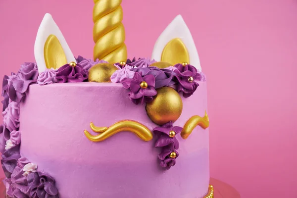 Cake unicorn with pink cream and flowers for girl\'s birthday on pink backgrounds. Close up.