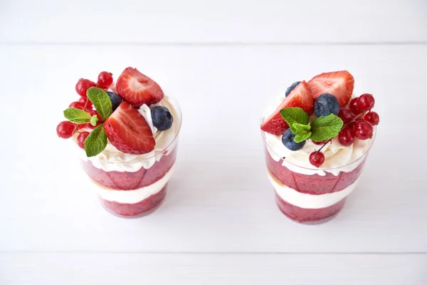 Trifle red velvet. Cake layered dessert in glass with fresh berry, mint leaves. Top view.