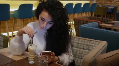 Bir restoranda kıvırcık saçlı bayanla telefonda çalışma ve kahve içme