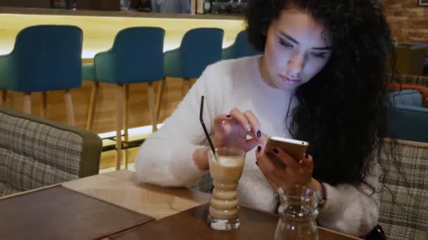 Schöne Dame mit lockigem Haar in einem Restaurant arbeitet am Telefon und träumt — Stockvideo