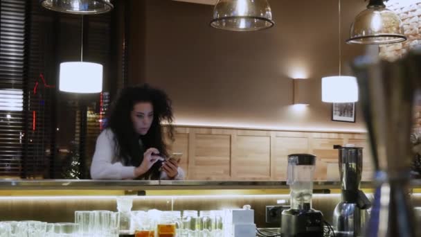 Belle fille avec les cheveux bouclés au bar toucher téléphone — Video