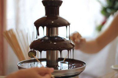 Çocuk elinde bir sopa bir çikolata çeşme içinde meyve bekle