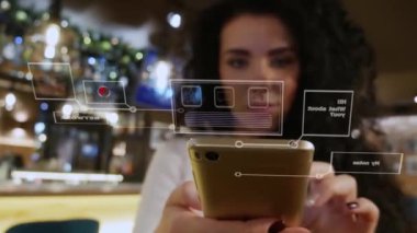 Bir restoranda kıvırcık saçlı güzel kız smartphone ile sanal arabirimi kullanır.