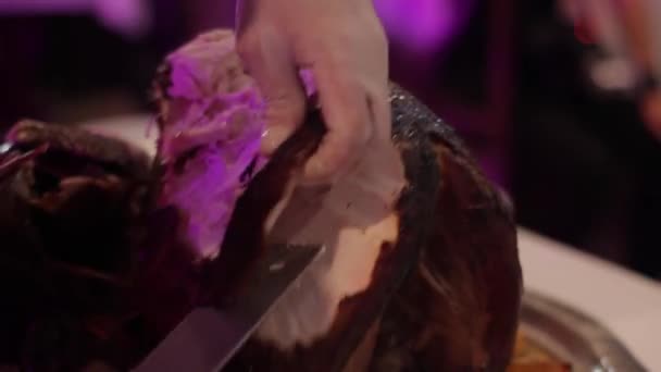 Chef coupe la viande juteuse d'une grande dinde sur un fond coloré — Video