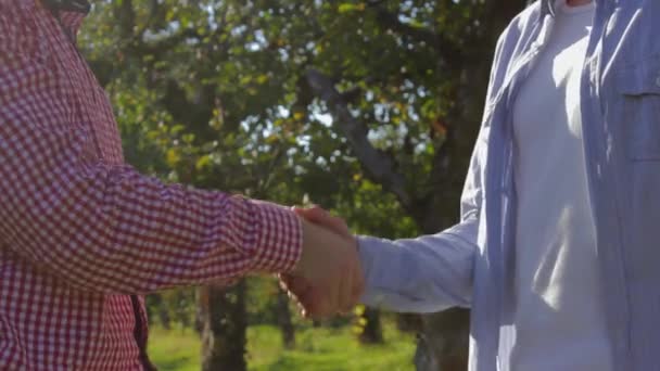 Due agricoltori irriconoscibili si stringono la mano e si preparano a concludere un accordo di alberi verdi — Video Stock