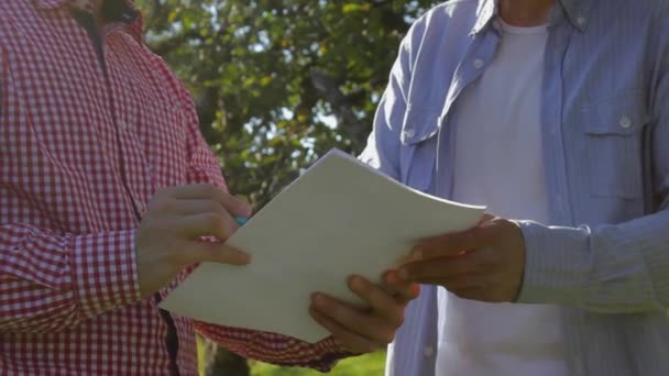 Двоє невпізнаваних фермерів уклали угоду в яблучному саду — стокове відео