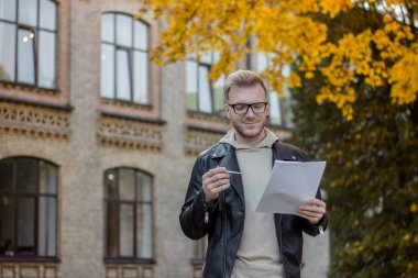 Rahat kıyafetler içinde mutlu bir öğrenci kağıt kalemle tutar ve onlara bakıyor
