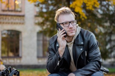 Rahat kıyafetler içinde rüya akıllı bir adam telefonda konuşuyor ve bir bankta oturan