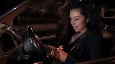 Güzel gülümseyen kız arabası ve telefonda konuşurken direksiyonun arkasında oturuyor