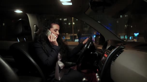 Glücklich lächelndes Mädchen, das hinter dem Lenkrad eines Autos sitzt und mit dem Smartphone spricht — Stockvideo