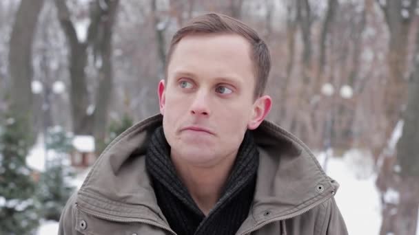 Portret van een geïrriteerd jongeman die permanent in een bos in de winter — Stockvideo