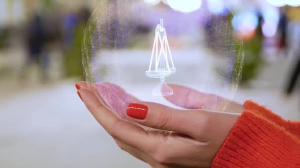 Female hands holding a conceptual hologram with balance scales — Stock Video