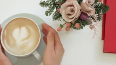 Eller bir fincan Cappuccino crema üzerinde bir kalp ile tutun