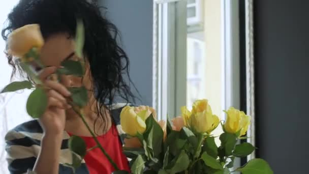 Beautiful curly woman forms a bouquet by the window — Stock Video