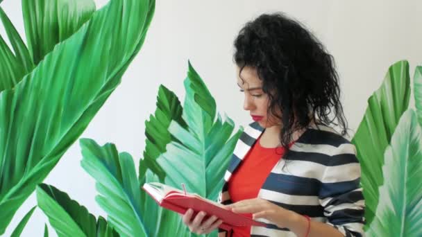 Menina lendo um livro perto da parede — Vídeo de Stock